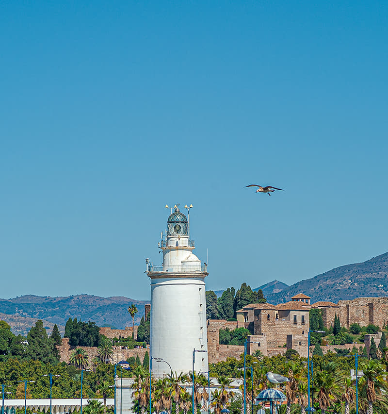 La Farola de Málaga, construida con piedra del Monte Gibralfaro, con la Alcazaba al fondo. .