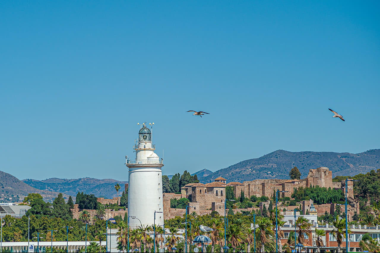 La Farola de Málaga, construida con piedra del Monte Gibralfaro, con la Alcazaba al fondo. .